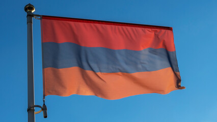 Variant of the flag of Armenia with alternative colors on the flagpole waving in the wind on a blue background.