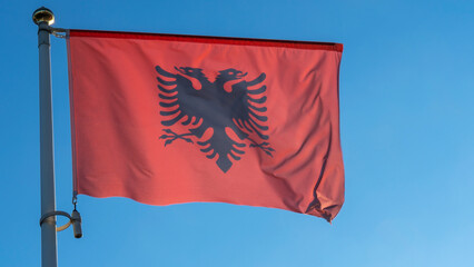 Albania national flag cloth fabric waving on the sky with beautiful sun light. Diplomacy concept.