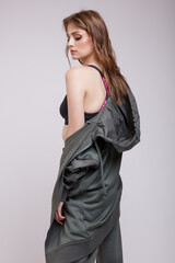Fototapeta premium High fashion photo of a beautiful elegant young woman in a pretty green tracksuit, jacket, pants, sports bra posing over white background. Slim figure. Studio shot.