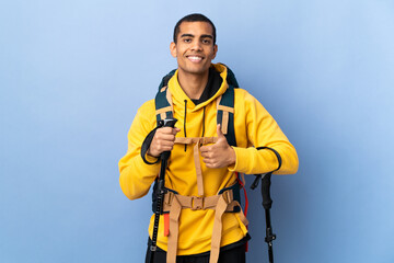 African American man with backpack and trekking poles over isolated background giving a thumbs up gesture