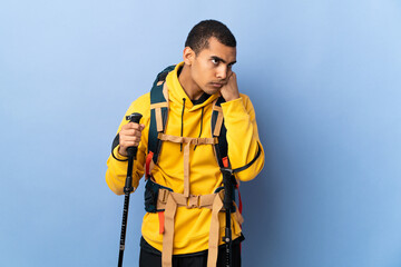 African American man with backpack and trekking poles over isolated background with tired and bored expression