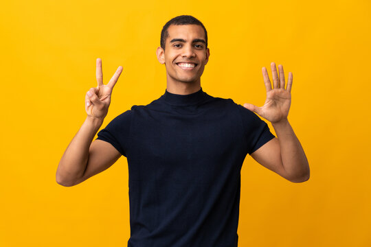 African American man counting numbres over isolated yellow background