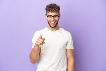 Delivery caucasian man isolated on purple background surprised and pointing front