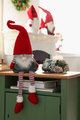 Obraz premium Cute Christmas gnome on wooden table in room with festive decorations
