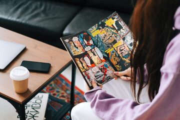 Fototapeta premium Woman reading comic book at home in living room. Rostov-on-Don, Russia. 25 January 2021