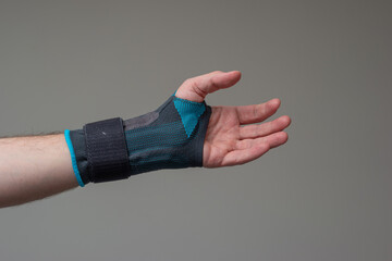 Velcro wrist stabilizer cast worn by Caucasian male hand. A blue split brace meant to aid Carpel...