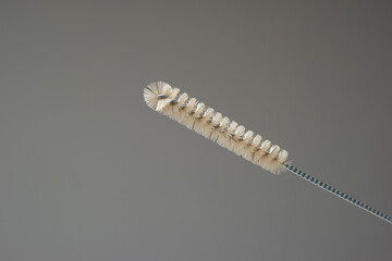 Bottle cleaning brush. Metal woven handle plastic brush, close up studio shot, isolated on gray background