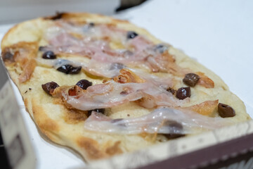 Italian pinsa with guanciale sausage and olives. Delicious and typical mediterranean food for take away.