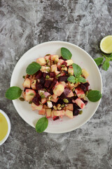 Flat lay plate of beet apple and pumpkin seed salad on a rustic kitchen counter