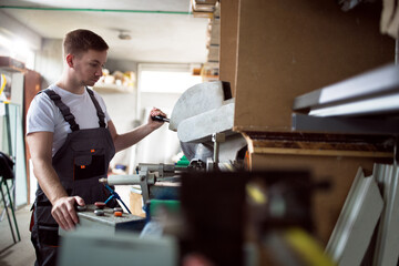 Worker in the workshop cuts the pvc profile