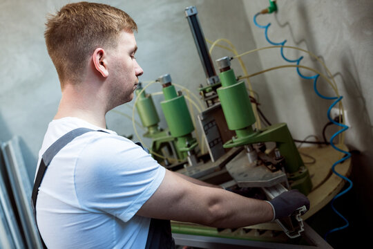 Worker operating welding machine in factory.