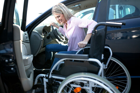 Physically challenged girl in pink shirt moving herself from the vehicle to the wheelchair