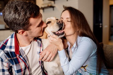 Young couple and their fluffy baby labrador retriever at home in the kitchen