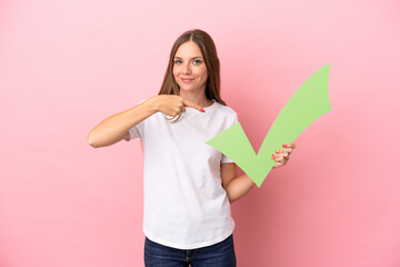 Young Lithuanian woman isolated on pink background holding a check icon and pointing it