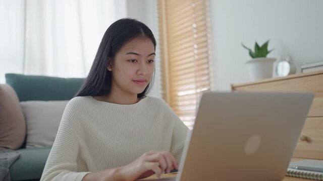 Beautiful Asian woman using a laptop computer at home morning