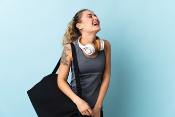 Young sport Brazilian woman with sport bag isolated on blue background laughing