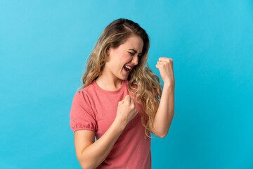 Fototapeta premium Young Brazilian woman isolated on blue background celebrating a victory