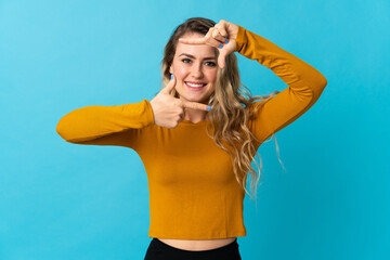 Young Brazilian woman isolated on blue background focusing face. Framing symbol