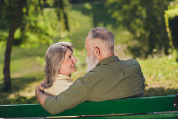 Profile photo of nice retired grey hair couple sit on bench look wear shirts outdoors walk in park