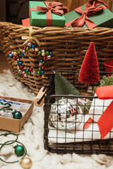 Christmas and New Year red and green decoration, bauble and ornament in a wooden and wire baskets on the carpet floor.