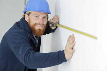 happy man measuring the wall with a measuring tape