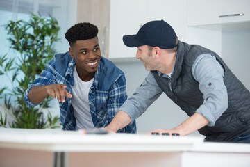 Fototapeta premium carpenter and apprentice installing luxury fitted kitchen