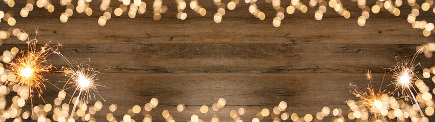 Frame of lights bokeh golden flares and sparkler isolated on rustic brown wooden texture - Holiday New Year's Eve Silvester New Year Party festive background banner panorama greeting card