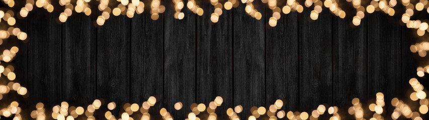 Frame of lights bokeh golden flares, isolated on rustic dark black wooden texture - Holiday New Year's Eve Silvester New Year Party festive background banner greeting card.