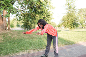 smiling African-American woman training with a rope in the open air