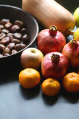 Pan with chestnuts, butternut squash and various fruit on dark background. Selective focus.