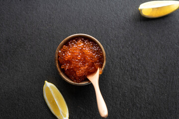  fresh red caviar with a wooden spoon on a dark background, in a ceramic bowl. copyspace