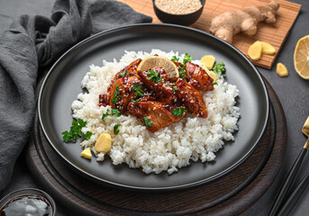 Teriyaki chicken with rice, sesame and ginger on a dark background.