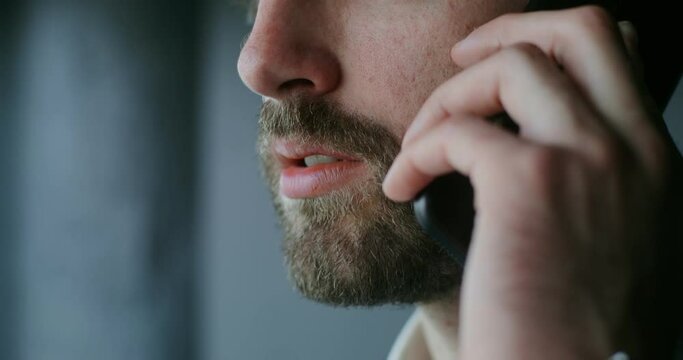 Young bearded man talking on a mobile phone, close-up