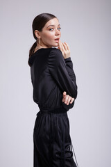 High fashion photo of a beautiful elegant young woman in a pretty black blouse, fringe trousers, accessories over white background. Studio Shot. Gathered dark hair. Slim figure