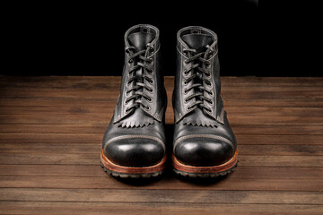 Hand crafted black leather high boots on wooden background