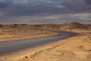 Fototapeta na wymiar Empty road in the black desert of Egypt in a storm