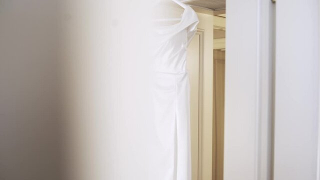 Light and delicate white brides dress on a hander. Wedding dress, indoors