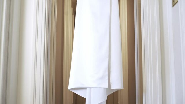 Light and delicate white brides dress on a hander. Wedding dress, indoors