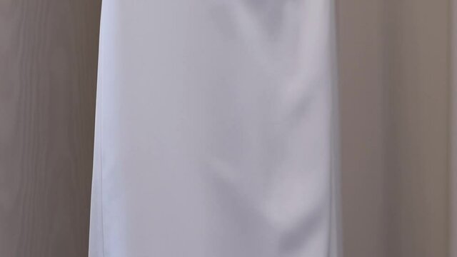Light and delicate white brides dress on a hander. Wedding dress, indoors