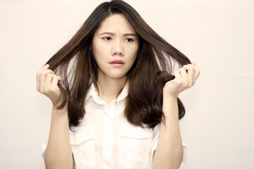 Fototapeta premium Asian beautiful women wear white t-shirt are holding and watching her hair with worry and unhappy cause by hair loss and dry or damage