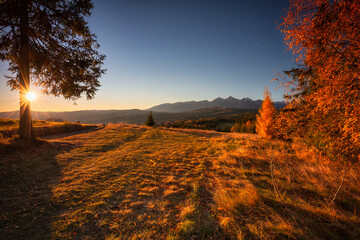 The first rays of the rising sun over the autumnal Tatra Mountains. The pass over Lapszanka. Poland