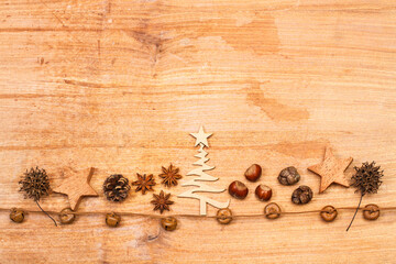 Naklejka premium Composición de Navidad con piñas secas, árbol, estrellas, castañas, anis estrellado y cascabeles sobre un fondo de madera rústico. Vista superior. Copy space