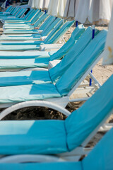 Fototapeta na wymiar Empty blue sunbeds on a modern beach
