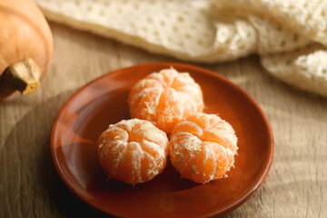 Peeled tangerines, butternut squash, open book, reading glasses and cozy blanklet. Hygge at home. Selective focus.
