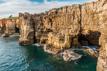 Fototapeta na wymiar Cliff with cave and waves crashing on the rocks in Boca do Inferno, Cascais PORTUGAL