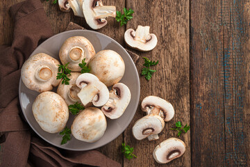 Raw mushrooms on a wooden background. Fresh champignons.