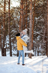 Cute couple is spending time outdoors in winter in the countryside, Christmas holidays.