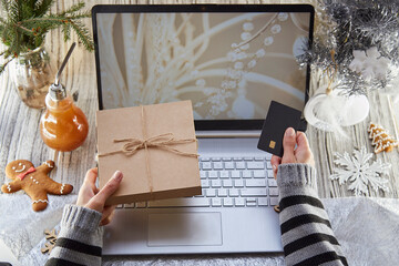 Woman searching and buying Christmas holidays gift online by laptop. Christmas decorations...