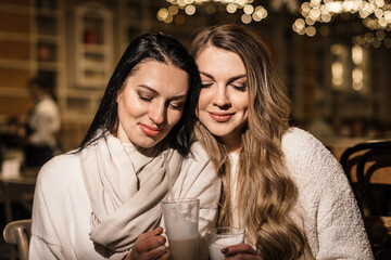 couple drinking coffee in the cafe. two beautiful young women in a cafe with mugs of coffee are sitting close to each other in a romantic setting