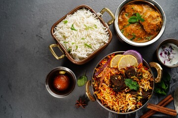 Indian veg non veg meal thali - mutton biryani, raita, malai kofta, basmati rice,  and gulab jamun, selective focus